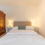 Schlafzimmer mit Bett, Nachttischen und antikem Schrank.