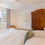 Schlafzimmer mit Bett, Holzschrank und Fenster mit Blick auf Außenbereich.