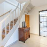 Eingang mit Treppe, Holzschrank und Glastür zum Flur.