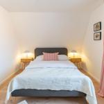 Schlafzimmer mit Bett, Nachttischen und Vorhängen an Fenster