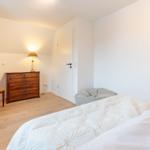 Schlafzimmer mit Bett, Schrank, Stuhl und Lampe.