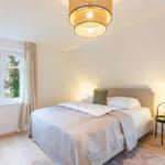 Schlafzimmer mit Bett, Fenster und Deckenleuchte.