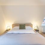 Doppelbett mit grünem Kissen, zwei Nachttische und Fenster.