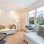 Wohnzimmer mit zwei Sofas, Tisch und Fenster mit Blick auf Garten.