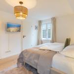 Schlafzimmer mit Bett, Fenster und Deckenleuchte.