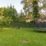 Garten mit Trampolin, Grillplatz und Rasenfläche.