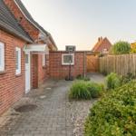 Hinterhof mit Basketballkorb, Steinweg und Hecken.