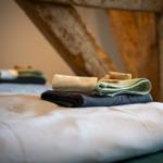 Faltbare Handtücher liegen auf einem Bett mit weißer Bettwäsche.