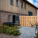 Hinterhof mit Sitzgelegenheiten und Holzzaun. Holz- und Ziegelhaus mit Fenstern.