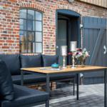 Außenbereich mit Sofa, Tisch und Blumen vor Backsteinmauer