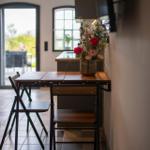 Esstisch mit Stühlen und Blumenarrangement vor Küchenbereich.