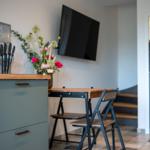 Küche mit Esstisch, Stühlen und Wandfernseher