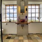 Bad mit Waschbecken, Fenstern und Dusche.