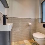 Badezimmer mit Waschbecken, Toilette und Fenster.