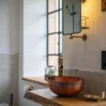 Badezimmer mit Kupferspüle, Holzwaschtisch und Spiegelschrank