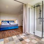 Schlafzimmer mit Doppelbett und angrenzender Dusche mit Glasabtrennung.