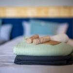 Gefaltetes Handtuch und zwei Holzstifte auf Bett mit Kopfteil.