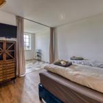 Schlafzimmer mit Doppelbett, Fernseher und Blick in angrenzenden Raum.