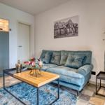 Ein Wohnbereich mit blauem Sofa, Holztisch und Wandbild.