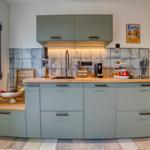 Küche mit hellblauen Schränken, Holzoberfläche und Steinrückwand.