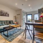 Wohn- und Essbereich mit Sofa, Tisch und Stühlen. Fenster und Tür zur Aussicht.