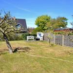 Hinterhof mit Grasfläche, Bäumen und Strandkorb. Hinterhof mit Holzzaun und Gartenmöbeln.