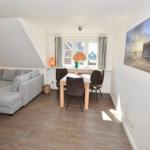 Wohn- und Essbereich mit Sofa, Tisch und Stühlen unter Dachschrägen.