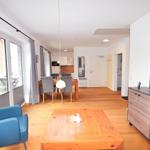 Wohn- und Essbereich mit Holzboden, blauer Sessel und Fernseher.