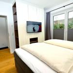 Schlafzimmer mit Bett, Fernseher und Fenster mit Blick nach außen.