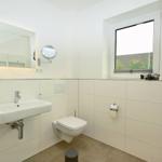 Badezimmer mit Waschbecken, Toilette und Fenster