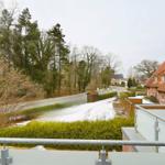 Blick von Balkon auf Straße, Bäume und roten Dach