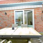 Terrasse mit Tisch und Stühlen vor rotem Ziegelhaus mit Schiebetür.