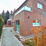 Apartmenthaus Emily mit Balkon, Holztor und gepflastertem Weg.