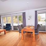 Wohn- und Essbereich mit Holzboden, Tisch und Stühlen, Sofa und Blick auf Balkon.