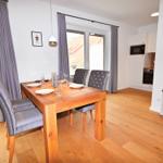 Esszimmer mit Holztisch, Stühlen und Blick auf Balkon