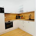 Küche mit weißen Schränken, Holzrückwand und Edelstahlgeräten.