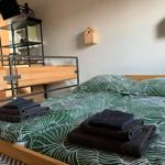 Doppelbett mit grün-weißem Bettbezug und gefalteten Handtüchern.