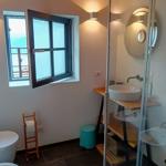 Badezimmer mit Dusche, Waschbecken und Fenster mit Meerblick.