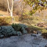 Garten mit Tisch, Stühlen und Picknicktisch unter Bäumen.
