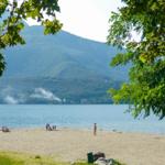 Strand mit Badeurlaubern und Bergen im Hintergrund