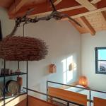 Schlafzimmer mit Holzbett, Fenster und Deckenbalken. Hängende Lampe aus Zweigen.