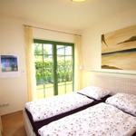 Zimmer mit Doppelbett, grünen Fenstern und Wandbild