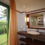 Badezimmer mit Waschtisch, Spiegel und Fenster zur grünen Außenansicht.