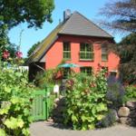 Rotes Haus mit grünem Tor und blühendem Garten.