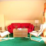 Ein Wohnzimmer mit rotem Sofa, zwei weißen Sesseln und einem Holztisch.