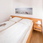 Ein Schlafzimmer mit Doppelbett, Holzrahmen und Nachttisch mit Lampe.