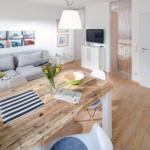Wohn- und Essbereich mit Holztisch, Sofa und Fernseher.