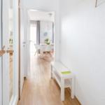 Flur mit Holzboden, weißer Bank und Blick in Esszimmer.