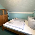 Zimmer mit Doppelbett, Holzschrank und gemalten Wänden.