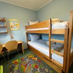 Ein Zimmer mit einem Holz-Etagenbett, einem Schreibtisch und einem Spielteppich.